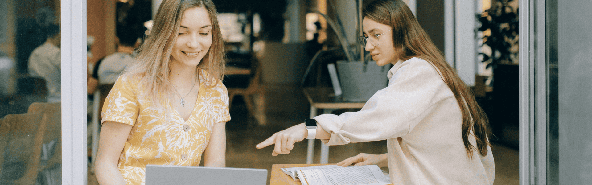 Two female university students smiling and talking in a common area (stock image)