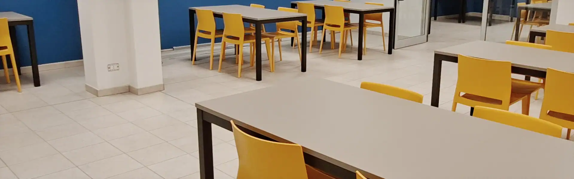Study room at PadovaCampus student residence in Padua with tables and yellow chairs