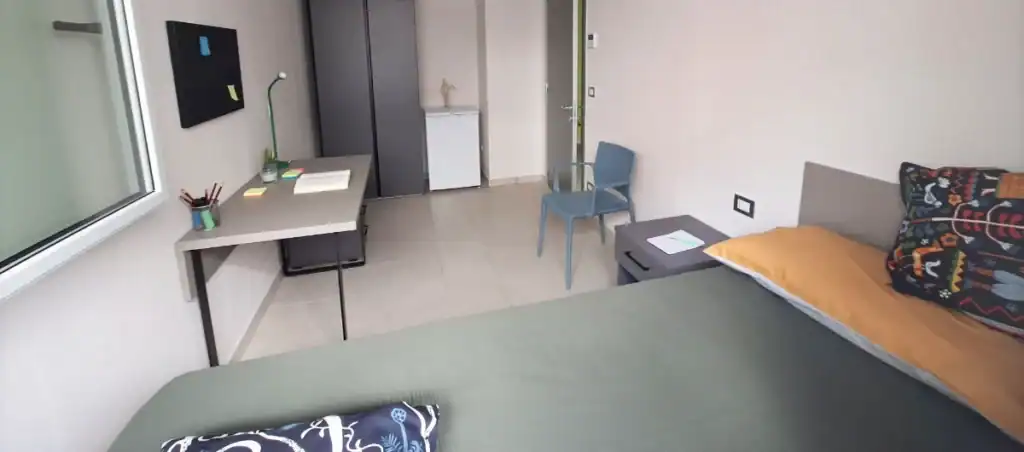 Camera singola arredata con letto, comodino e scrivania